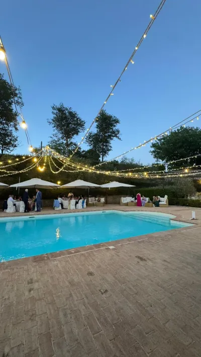 La piscina di Villa Torranca illuminata dalle luci sospese durante il ricevimento serale