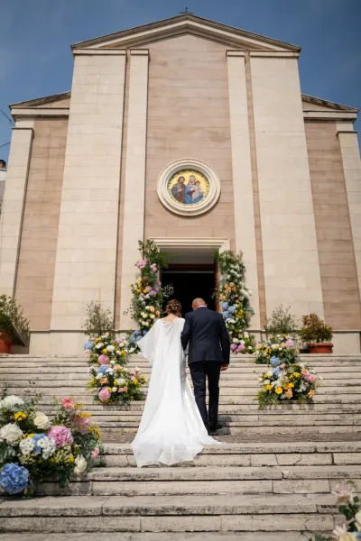 Carlo e Pilar salgono la scalinata fiorita della chiesa